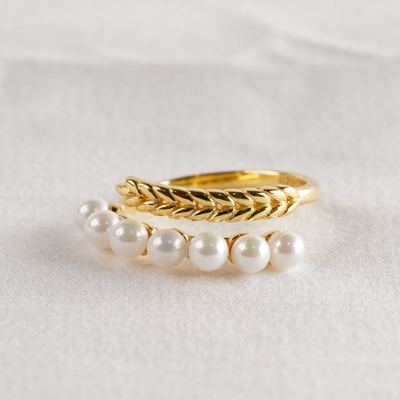 Pearlflow Ring, an 18K gold plated 925 silver ring set featuring a textured wheat pattern band and a pearl band, shown stacked together at an angle.