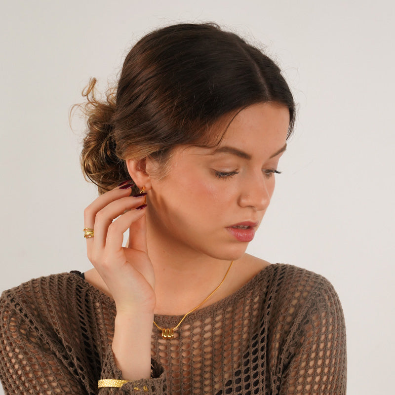 18K gold plated 925 silver twisted ring worn on model's finger, shown styled with matching jewelry pieces.