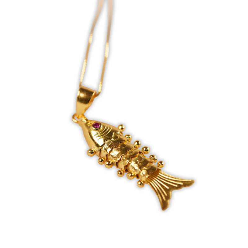 18K gold plated 925 silver fish pendant necklace with ruby eye detail, shown lying flat at an angle.