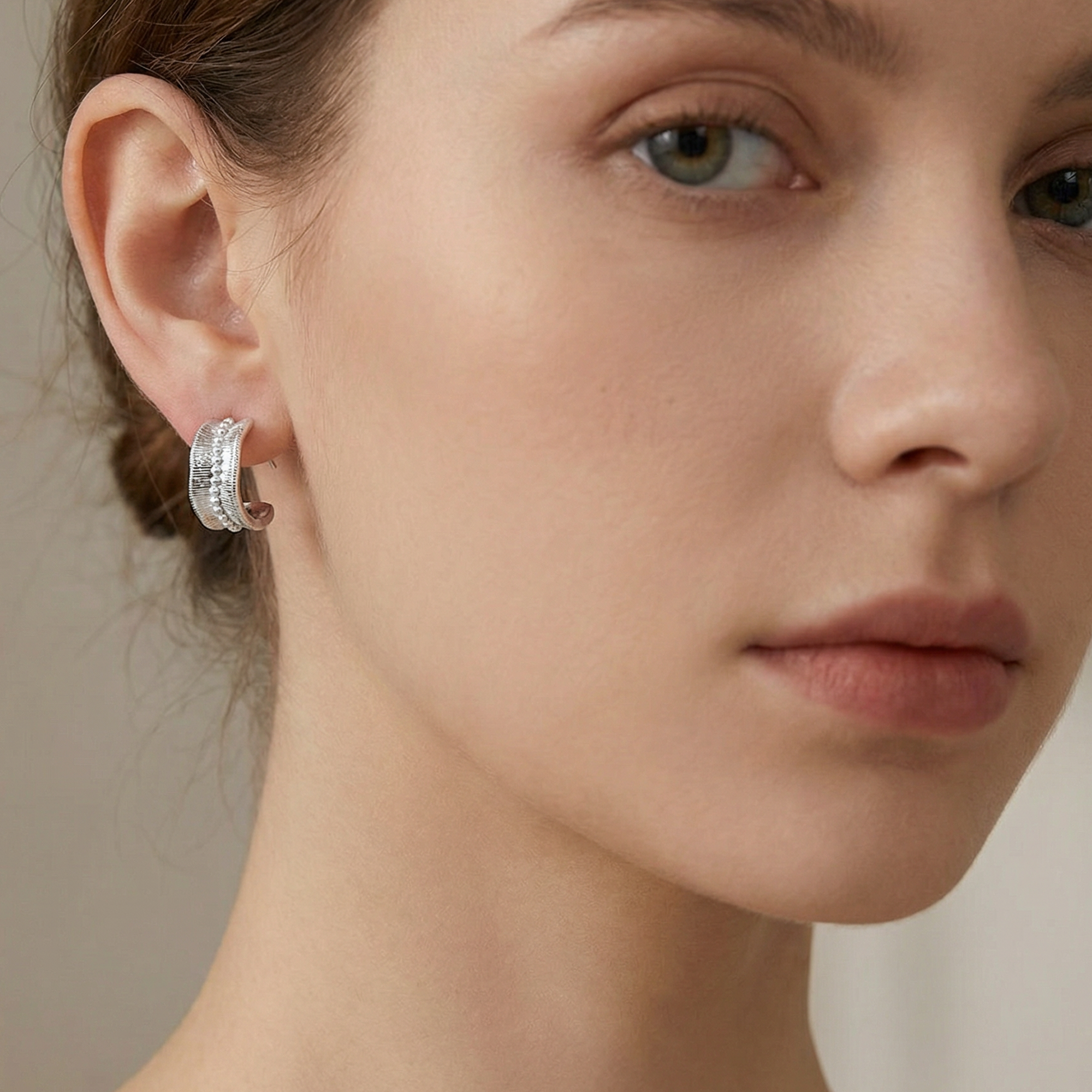 Silver hoop earrings with textured baguette crystal details worn on model's ear - Lucian Earrings Silver