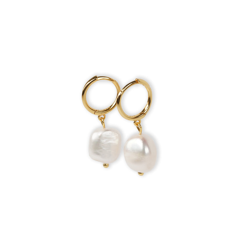 Margaux Earrings, a 14K gold plated platinum pair with hoop tops and dangling baroque pearls, shown flat lay.