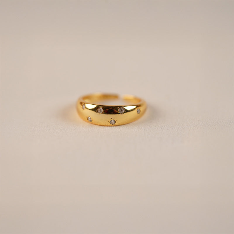 Zara Ring in 18K gold plated 925 silver with small inset crystals, shown at an angle on a neutral surface.