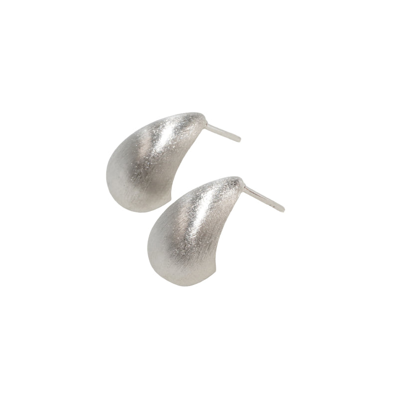 Chiara Earrings- Silver, a 925 silver earring pair with textured teardrop hoops, shown at an angle.